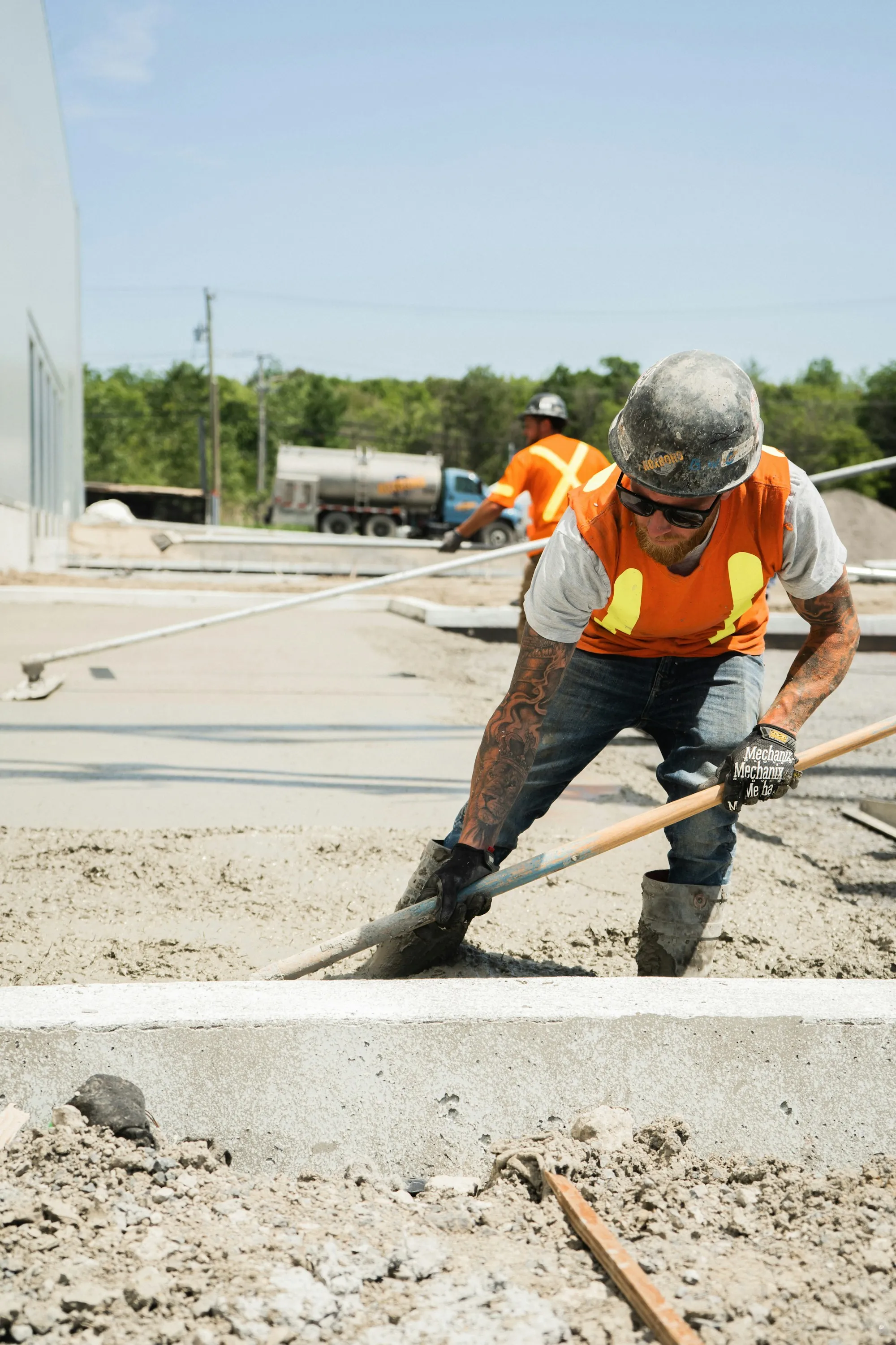 Worker spreading fresh concrete with a shovel